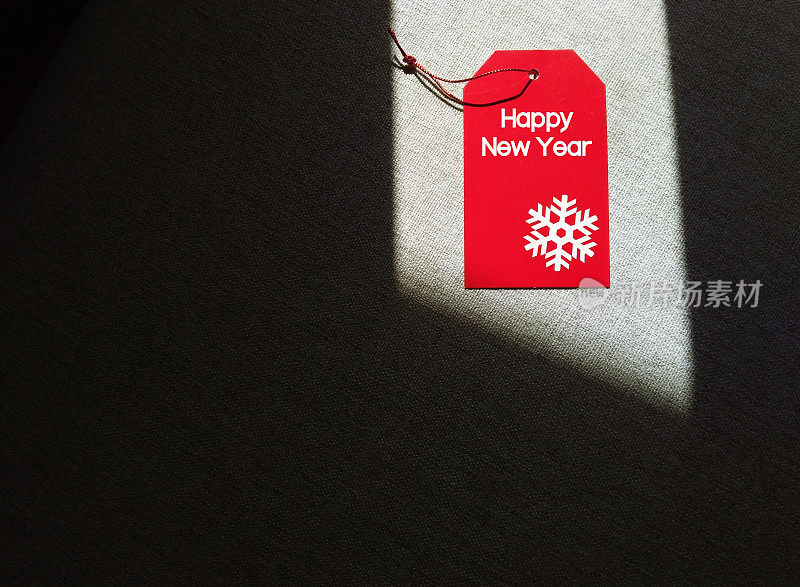 红色礼品吊牌以文字HAPPY NEW YEAR为正文空间暗影背景，概念新年节日庆祝贺卡，节日送礼，温馨祝福送给大家